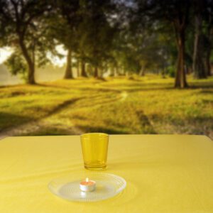 Coprimacchia color giallo in Tnt (tessuto non tessuto) con sopra un bicchiere giallo, un piatto ed una candela